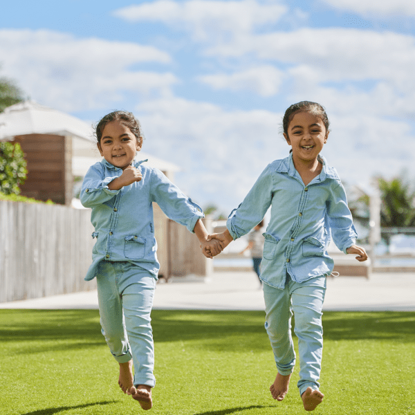 Two kids running while holding hands 